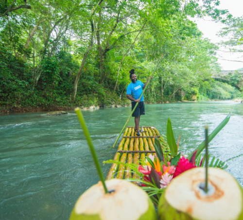 man rowing along a river on a bamboo raft