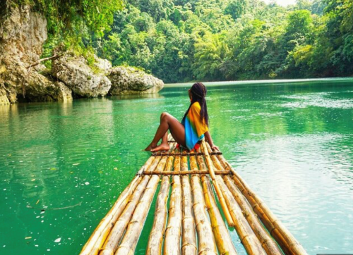 woman drifting along a river on a bamboo raft